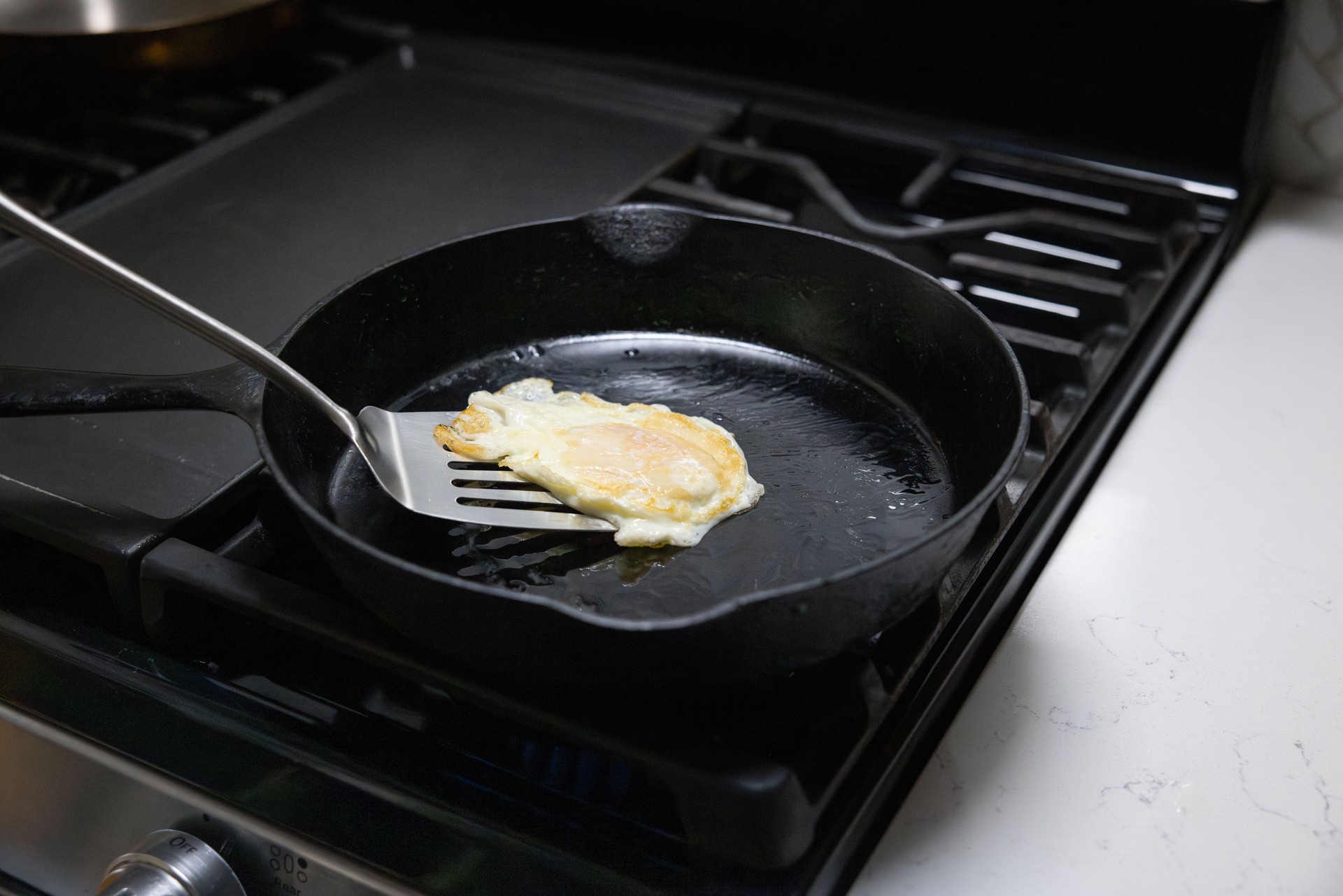 Cast iron pan on stovetop cooking an egg — toxin-free cookware including cast iron, carbon steel, stainless steel, and ceramic.